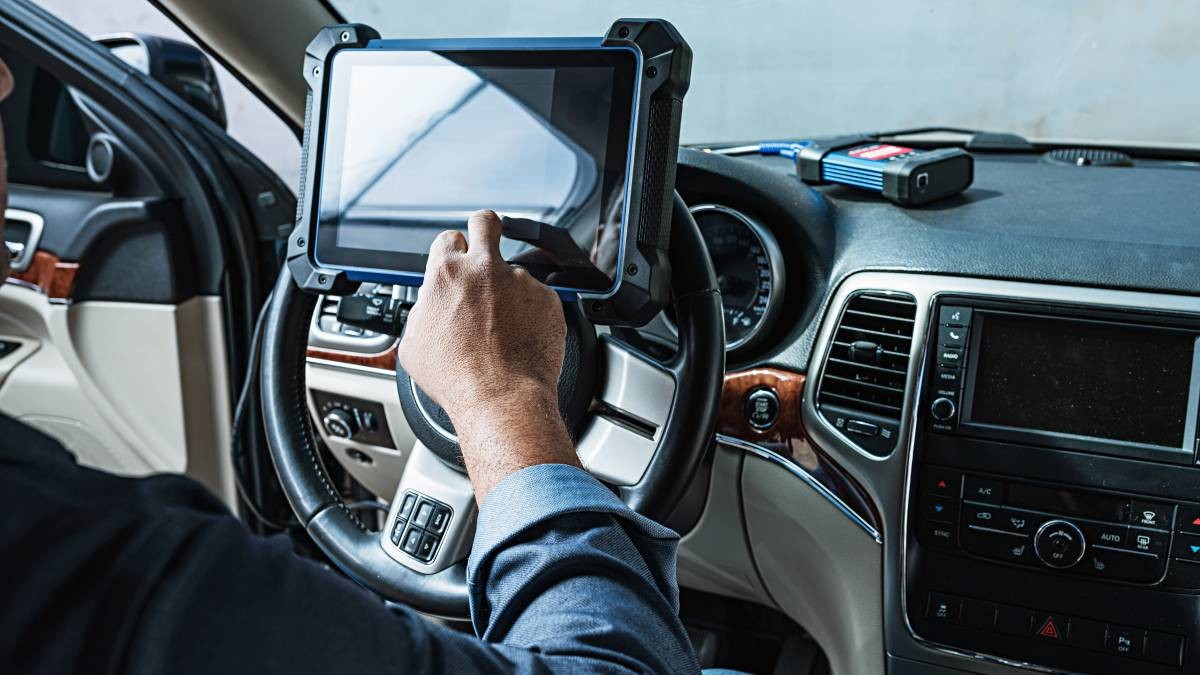 Mechanic diagnosing car with scan tool in garage