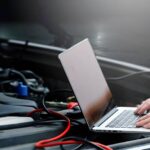 a mechanic using a diagnostic tool on a car's engine