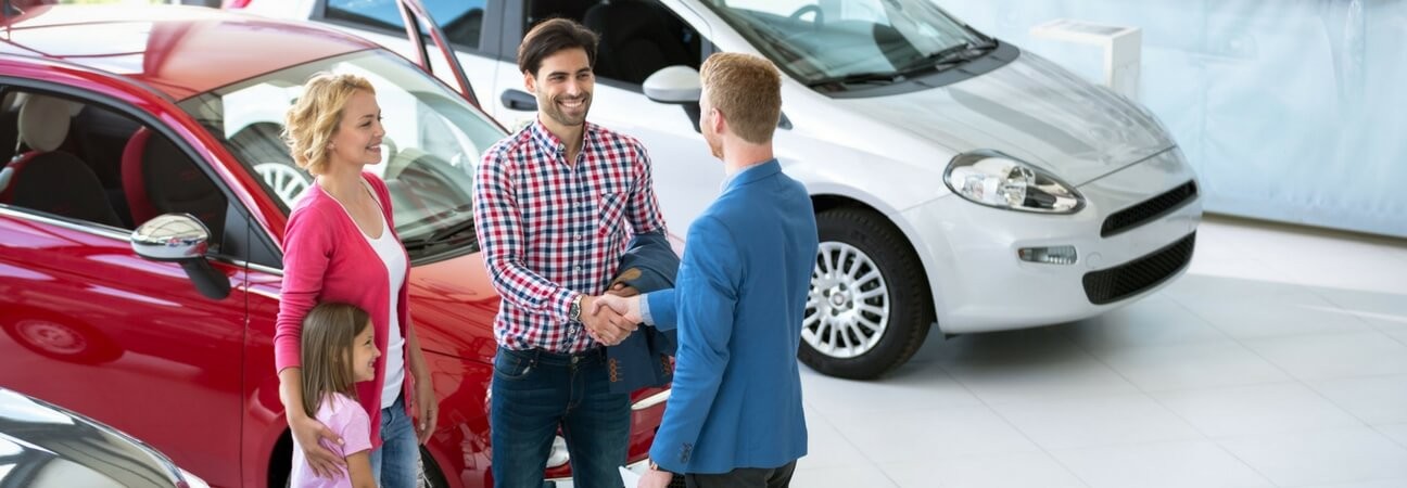 A dealership employee using car sales tools on a laptop, showcasing inventory management and vehicle pricing software interfaces.