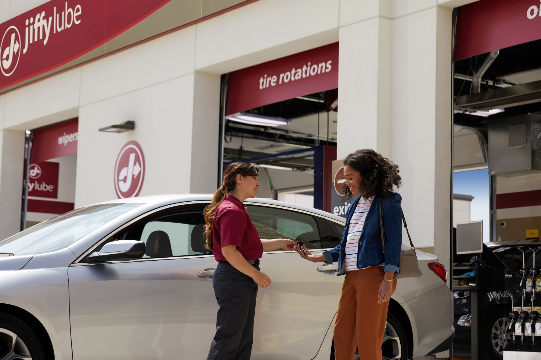 Woman talking with a Jiffy Lube technician about her car diagnostic test for vehicle problem analysis