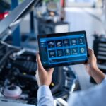 Professional mechanic using a diagnostic tablet to perform car diagnostics in a repair shop.