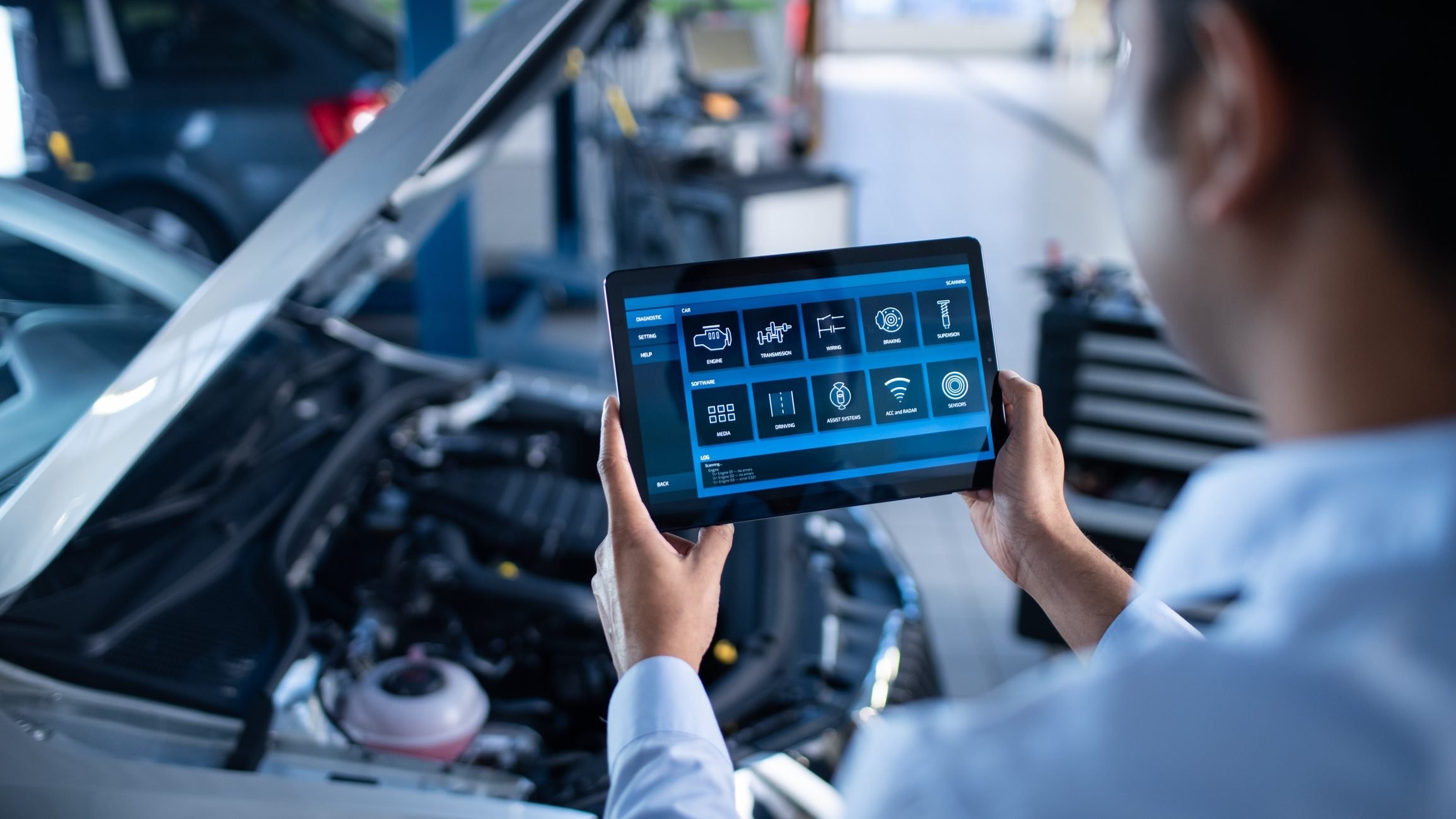 Professional mechanic using a diagnostic tablet to perform car diagnostics in a repair shop.