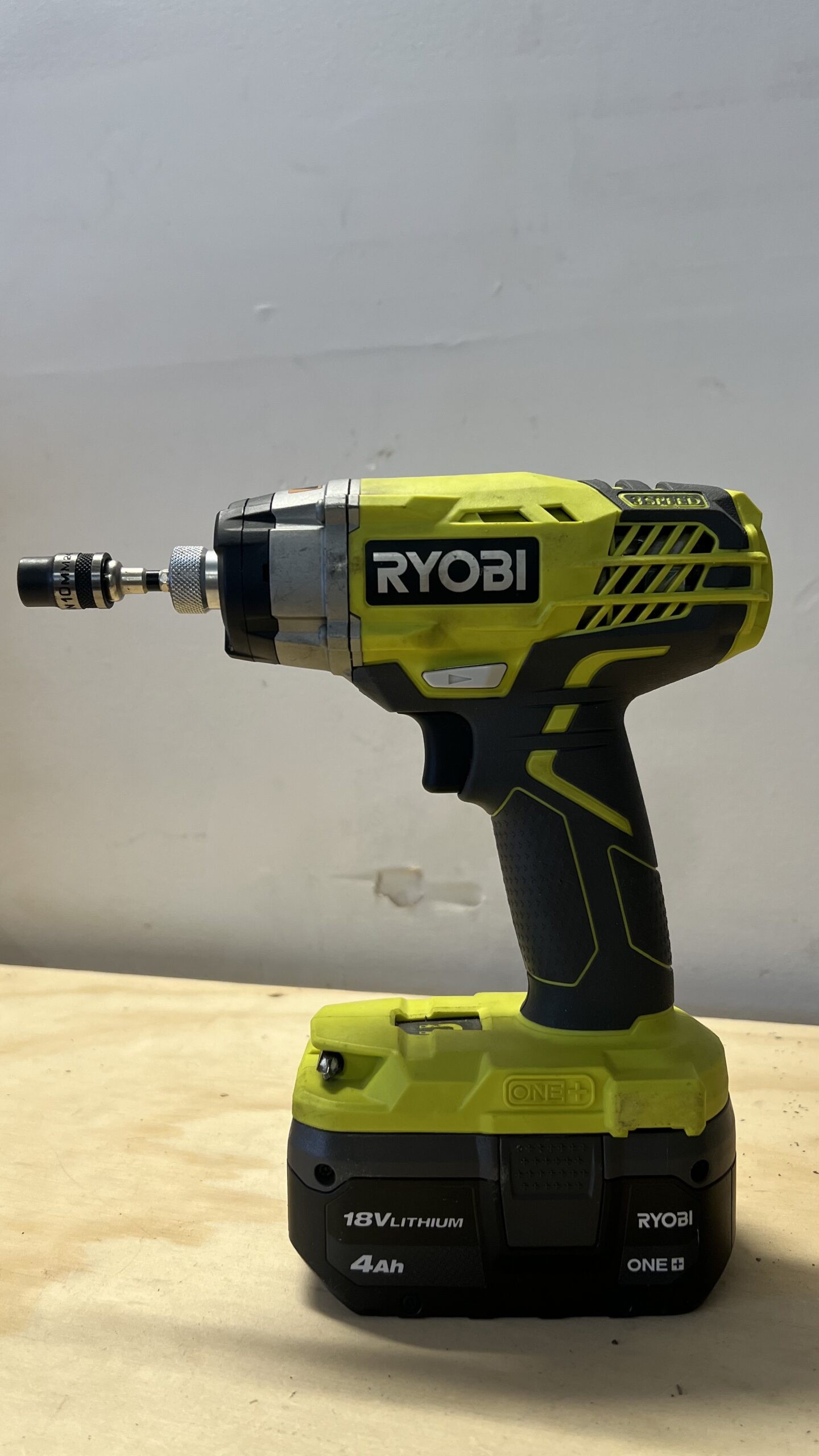 Close-up of a hand holding a Ryobi impact driver, showcasing its compact size and ergonomic design.