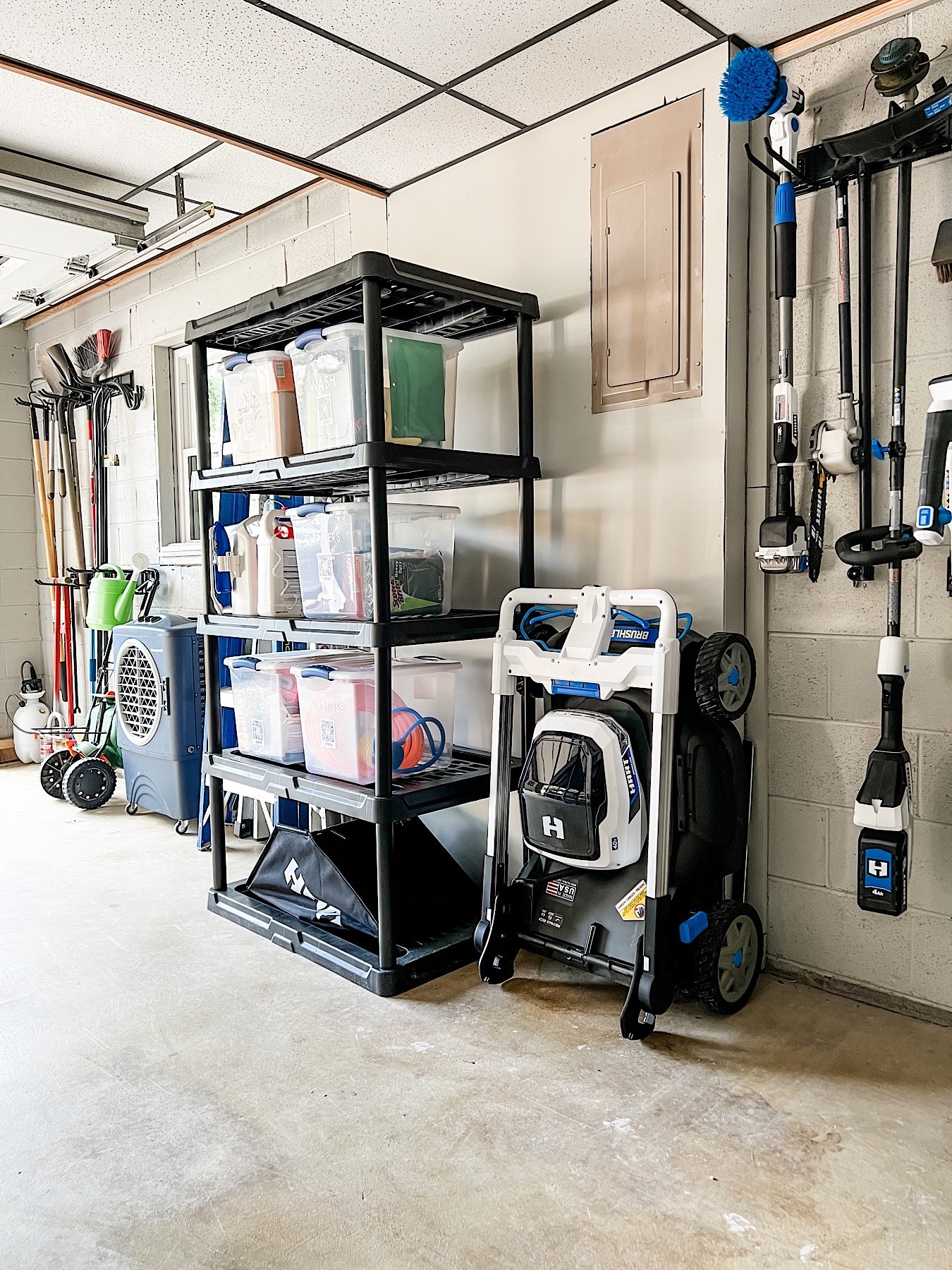 Garage shelving unit filled with organized storage bins and lawn care supplies