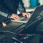 Car diagnostic testing being performed by a technician using a handheld scan tool to identify vehicle problems.