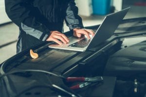 Car diagnostic testing being performed by a technician using a handheld scan tool to identify vehicle problems.