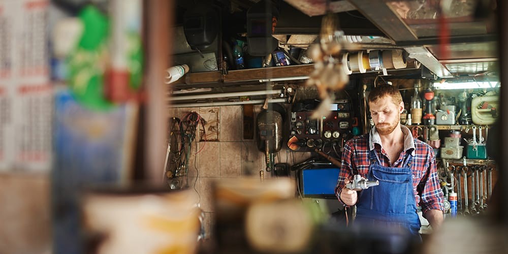 Mechanic inspecting car engine with tool