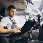 Mechanic using a diagnostic scanner connected to a car's OBD port to check for fault codes and car performance data.