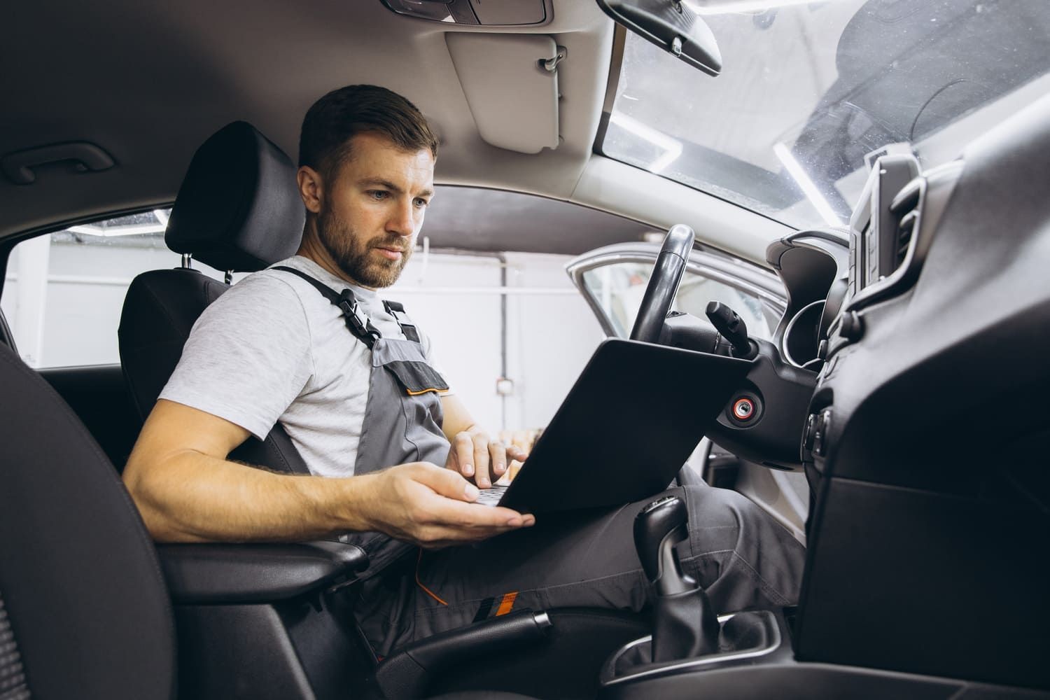 Mechanic using a diagnostic scanner connected to a car's OBD port to check for fault codes and car performance data.